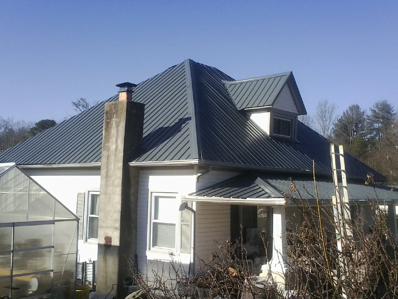 Dark blue standing seam metal roof on a white farmhouse with dormer — Slate & Tile Roof Repair by Roofing Brothers in Palmerton