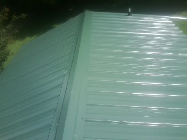 New green metal panels meeting at the ridge of a roof — Flat Roof Repair work by our crew in Palmerton
