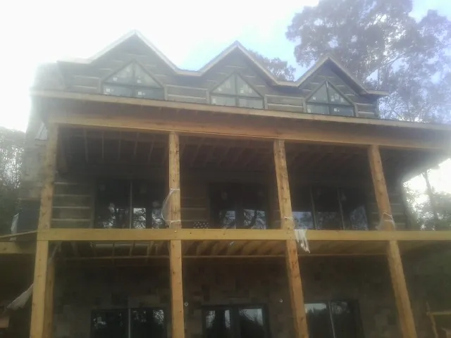 Dormers and porch framing on a large log home under construction — Roof Coating work by our crew in Palmerton