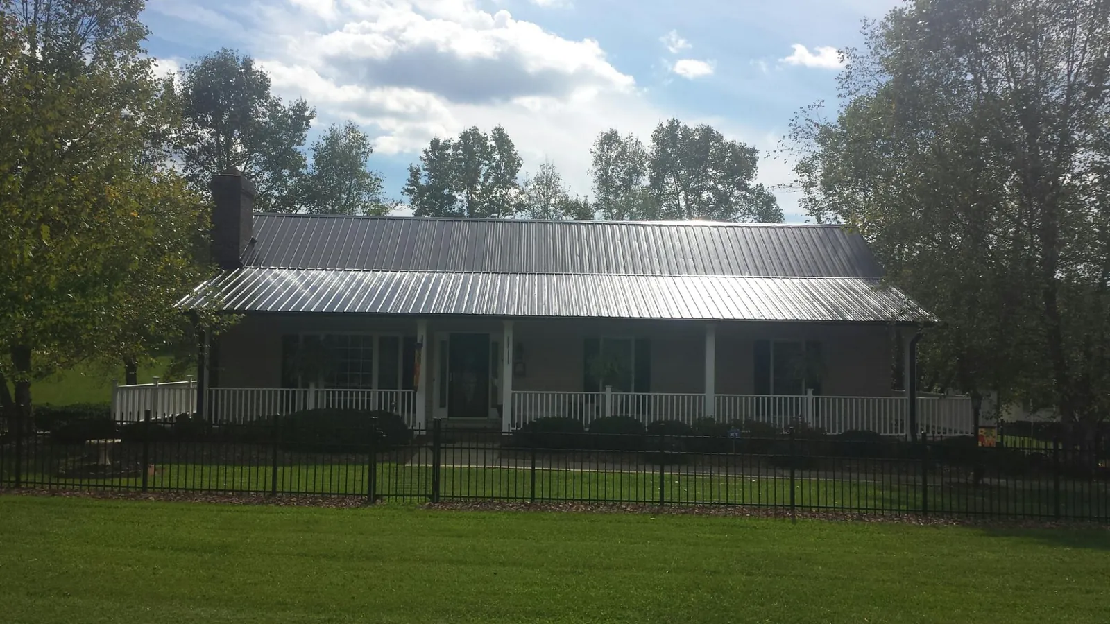 Gray metal roof on a brick ranch with a full width front porch — Gutter Guard Installation work by our crew in Palmerton