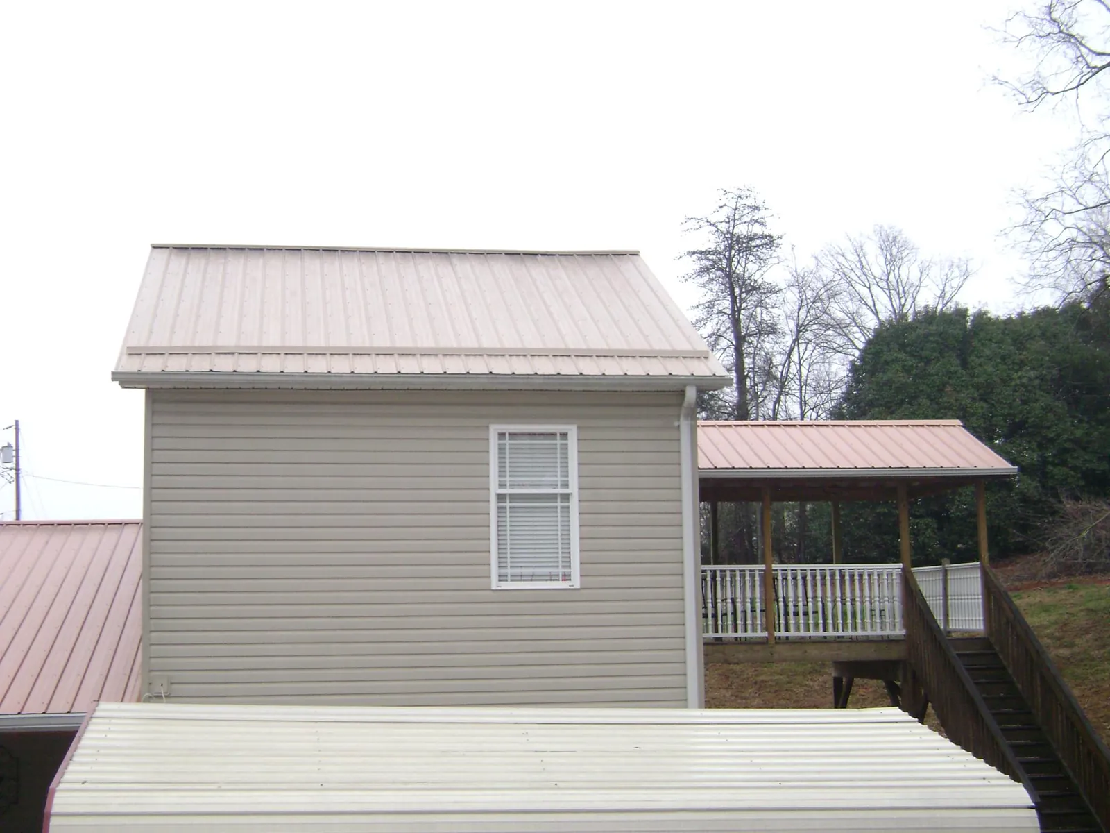 Tan metal roofs on a two story addition and attached porch, from a Roof Replacement job in Palmerton