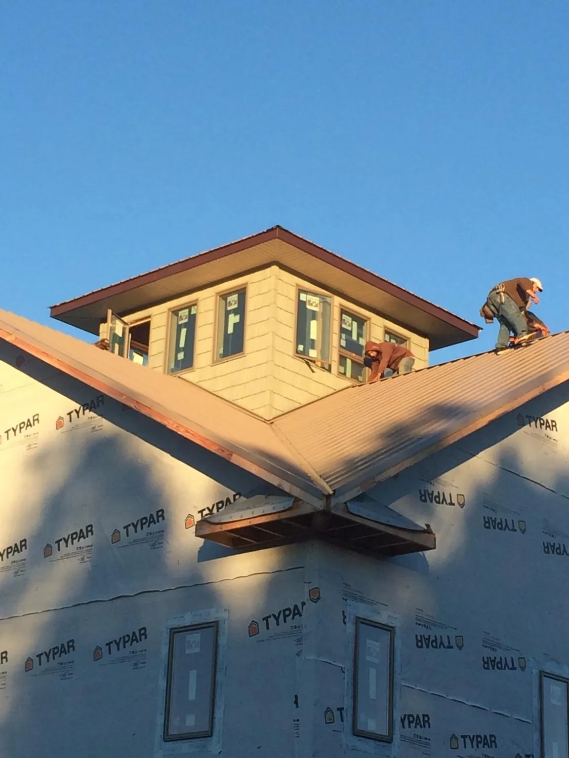 Roofers working around a rooftop cupola on a new metal roof at sunset — Roof Waterproofing in Palmerton by Roofing Brothers